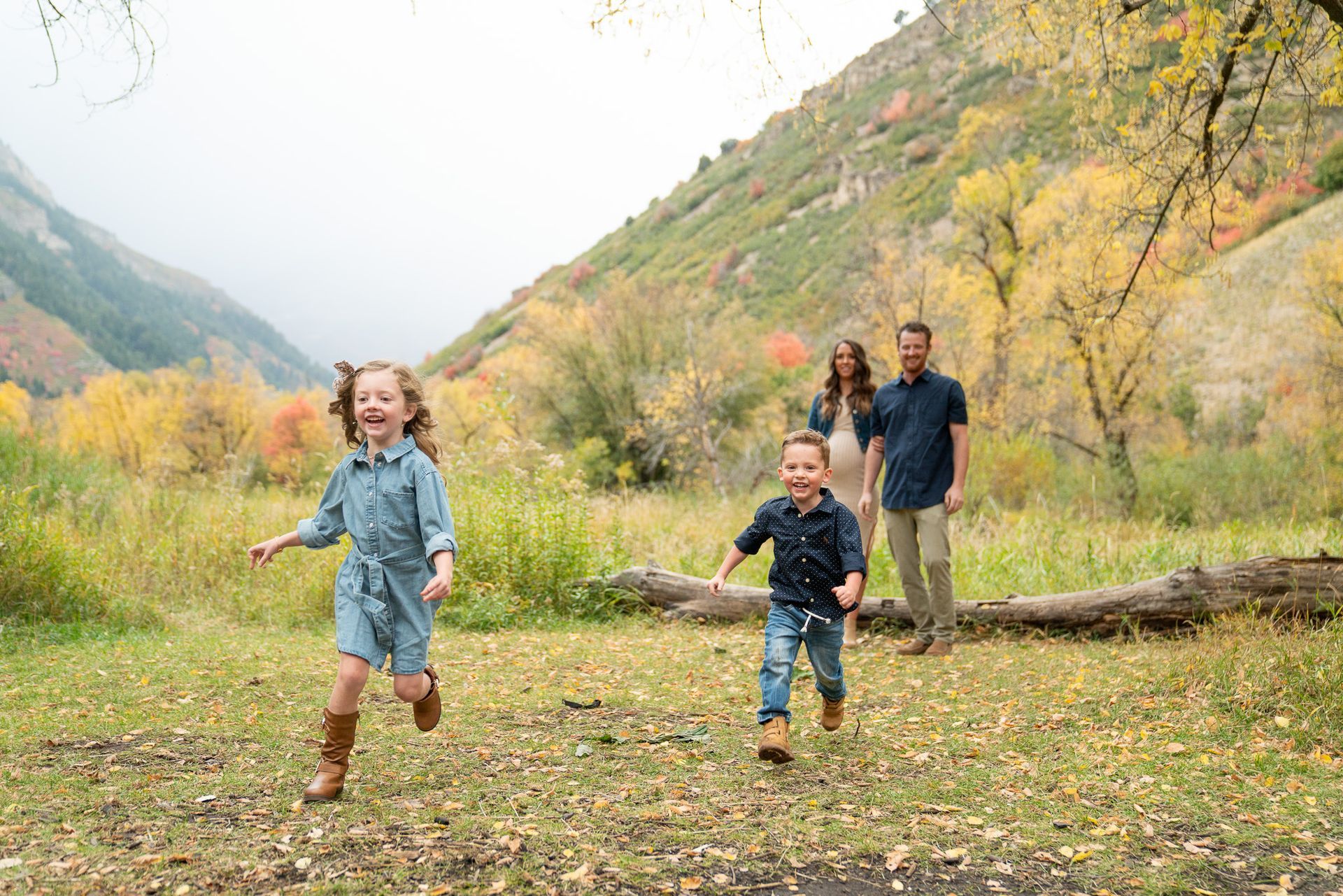 A family is running through a field in the mountains.