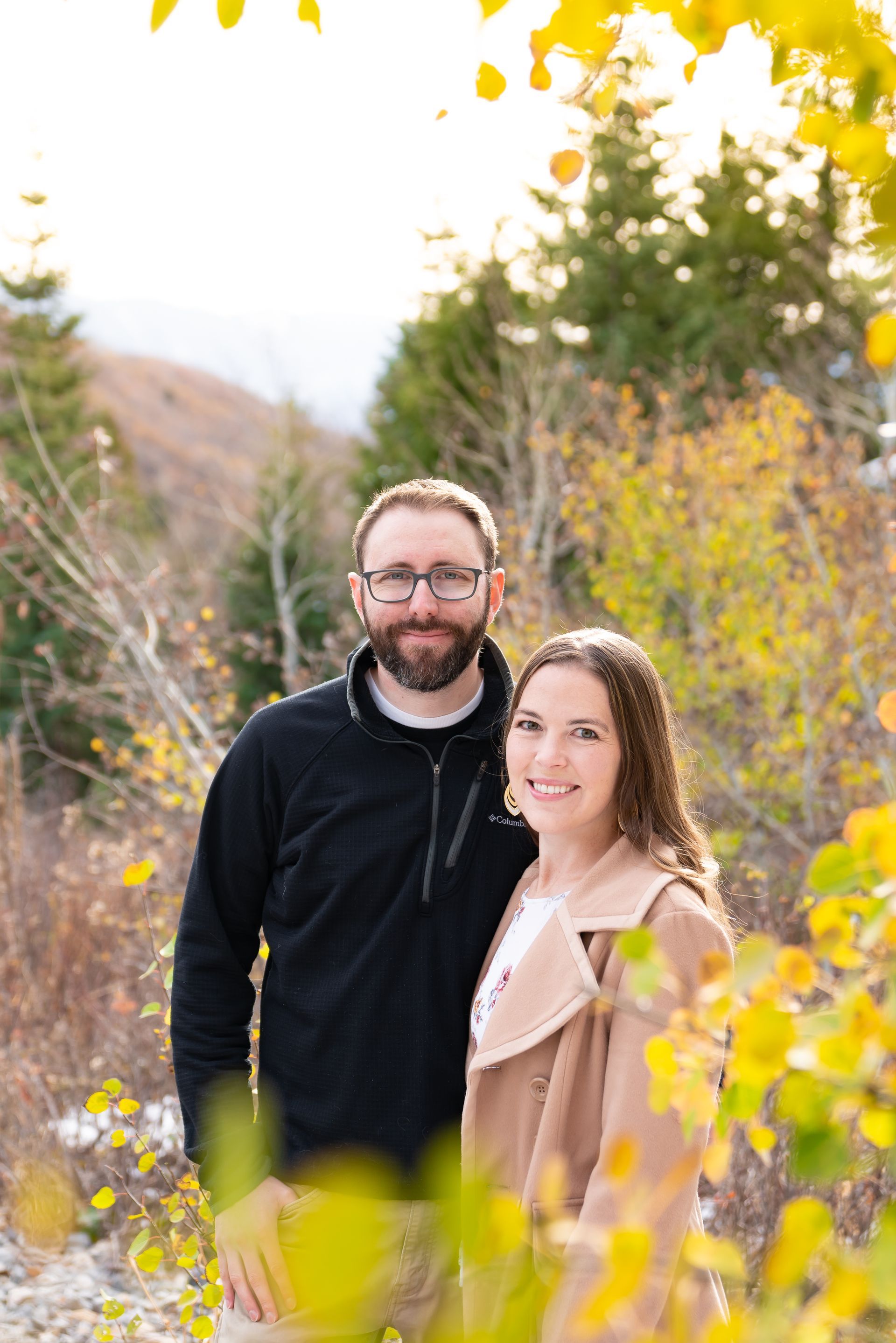 A man and a woman are standing next to each other in a forest.