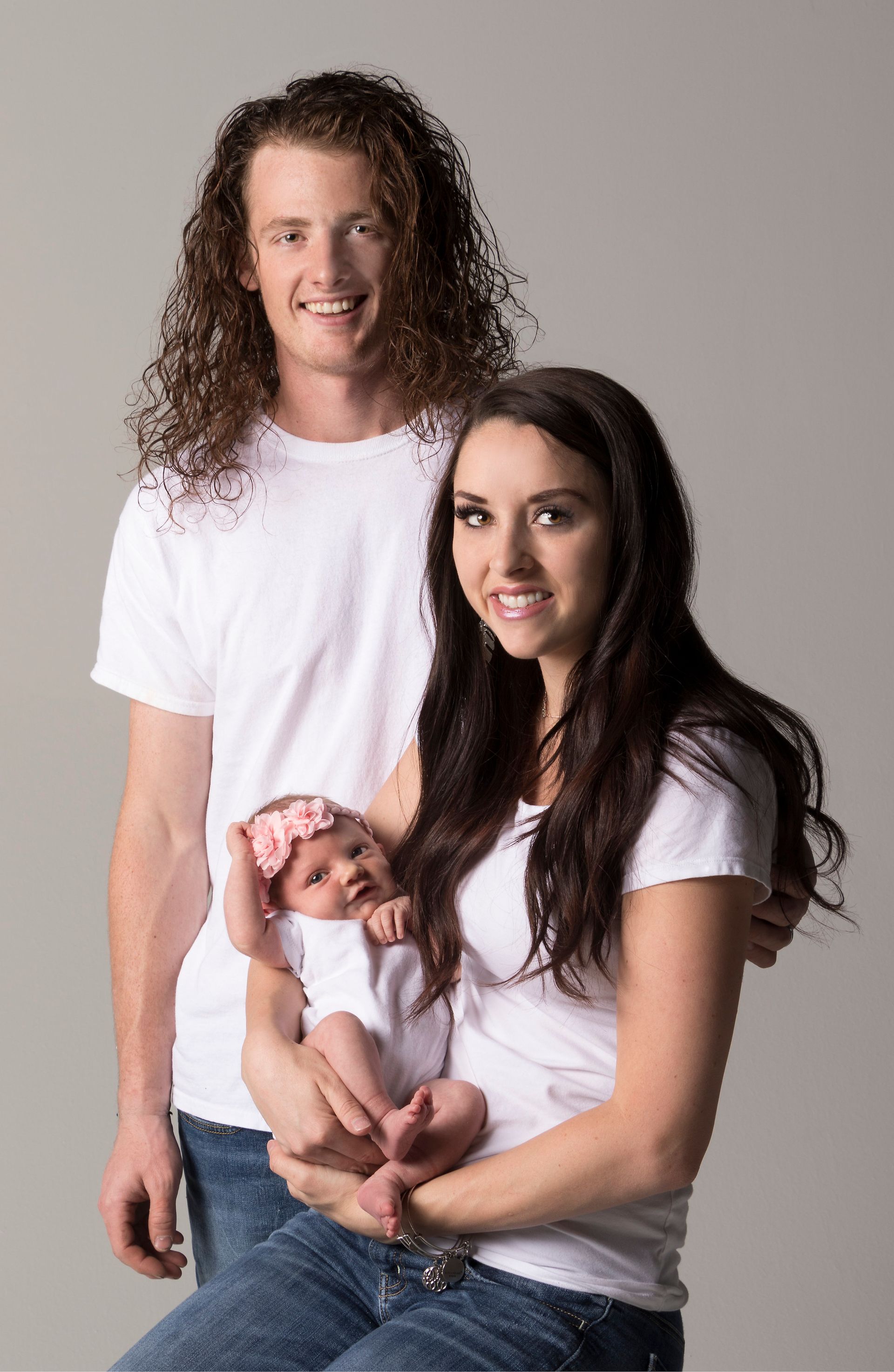 A man and a woman are holding a baby in their arms.