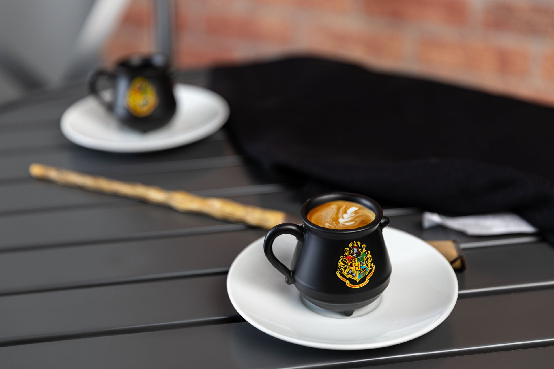 A cup of coffee is on a saucer on a table next to a wand.