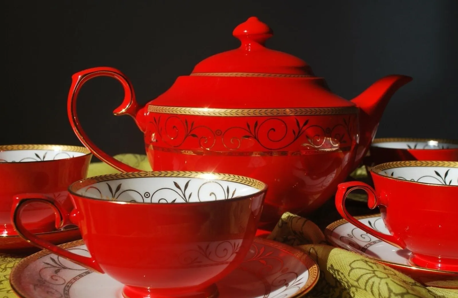 A red teapot and cups and saucers on a table