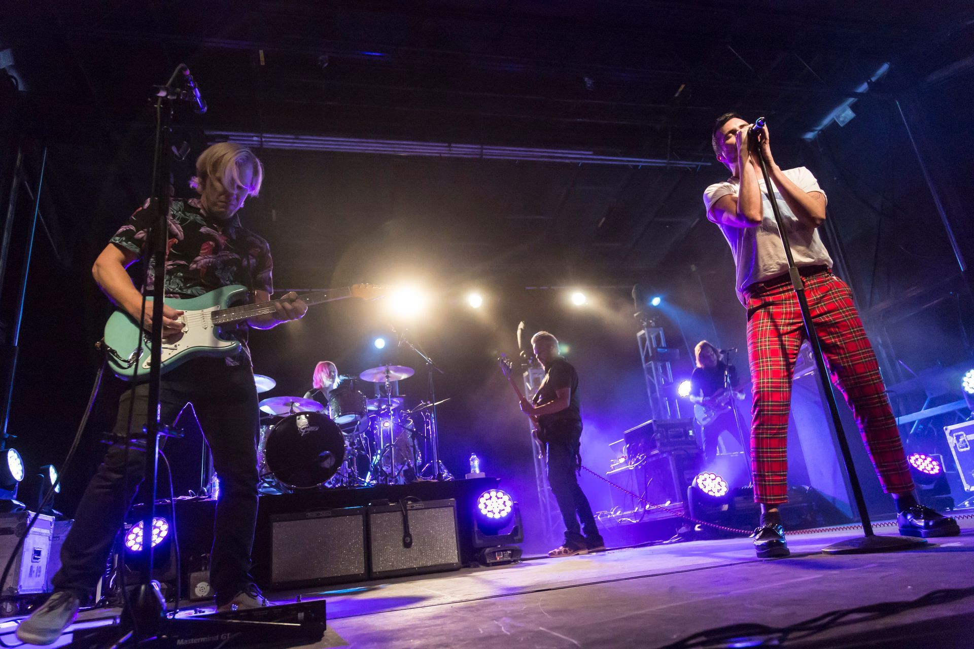 A group of people are playing instruments on a stage in a dark room.