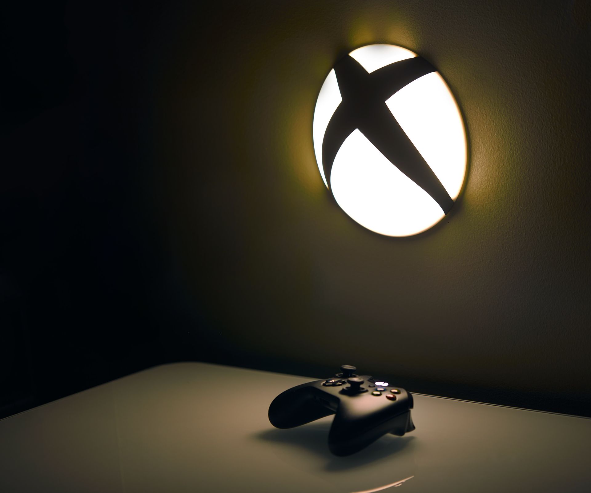 An xbox controller sits on a table under a light