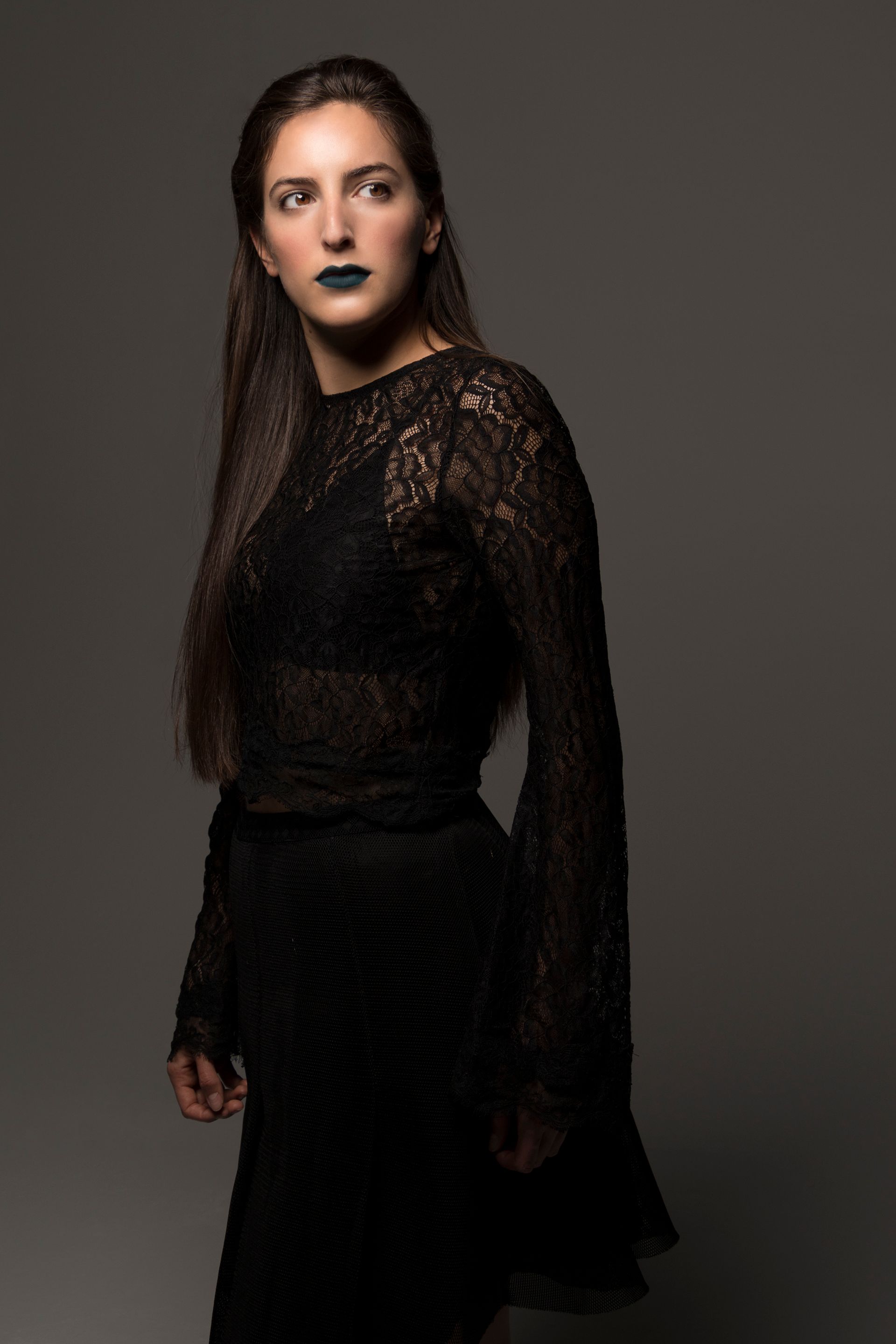 A woman is wearing a black lace top and black skirt.