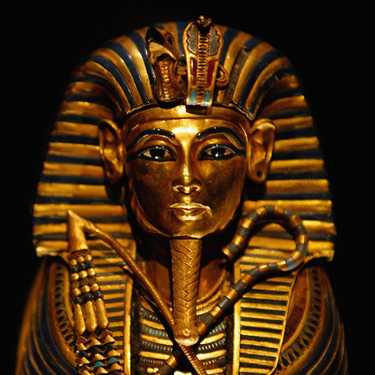 A statue of a pharaoh with a blue and gold crown