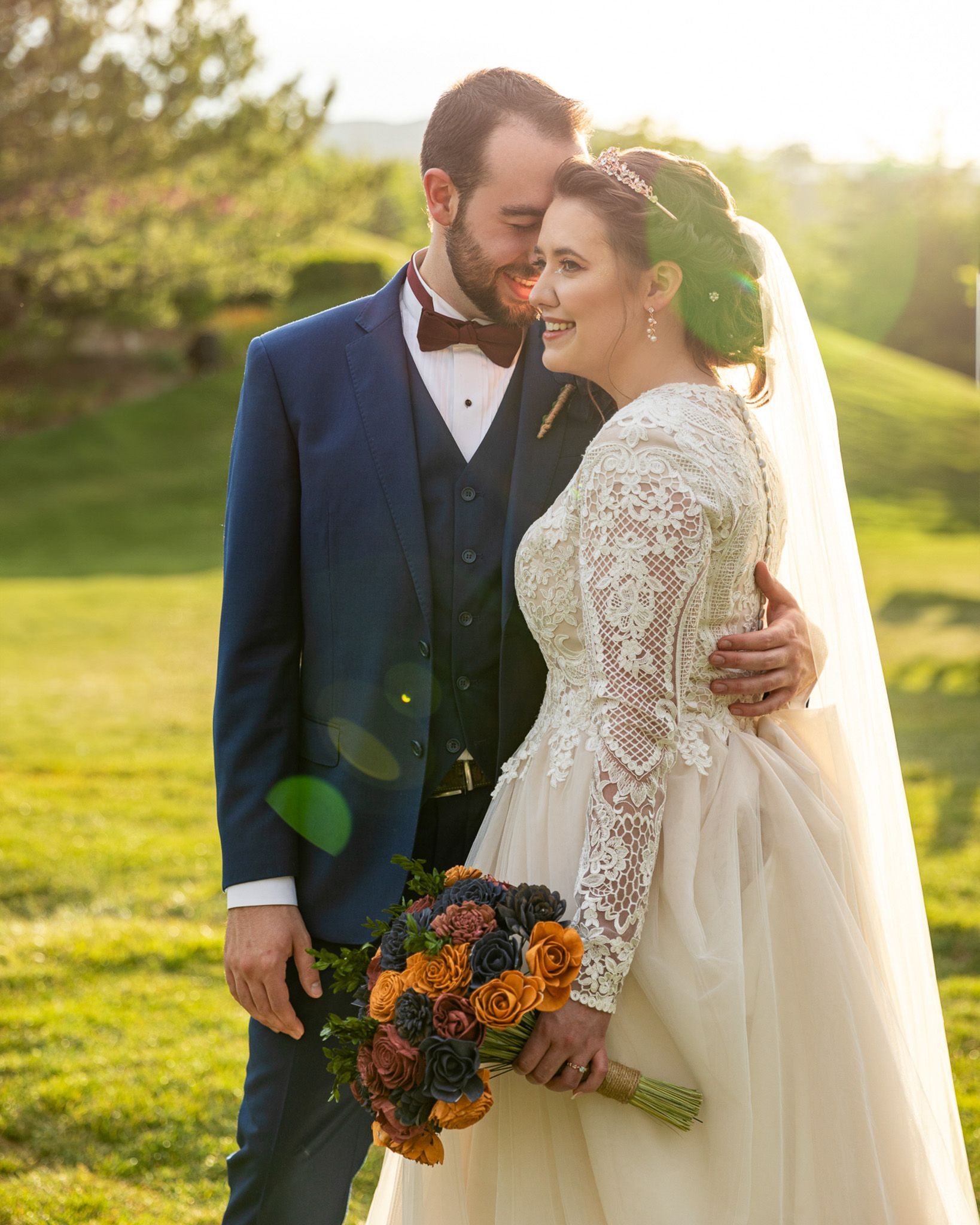 A bride and groom are posing for a picture in a field.