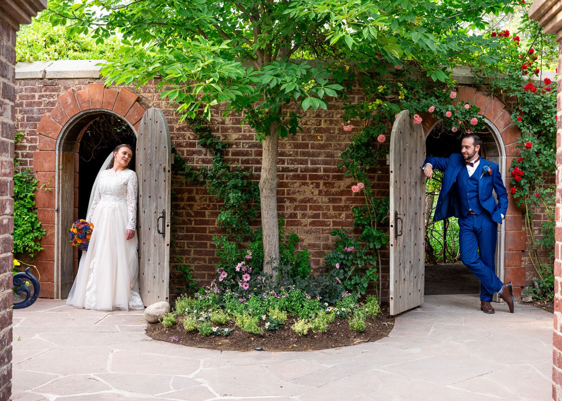 A bride and groom are posing for a picture in front of a brick wall.