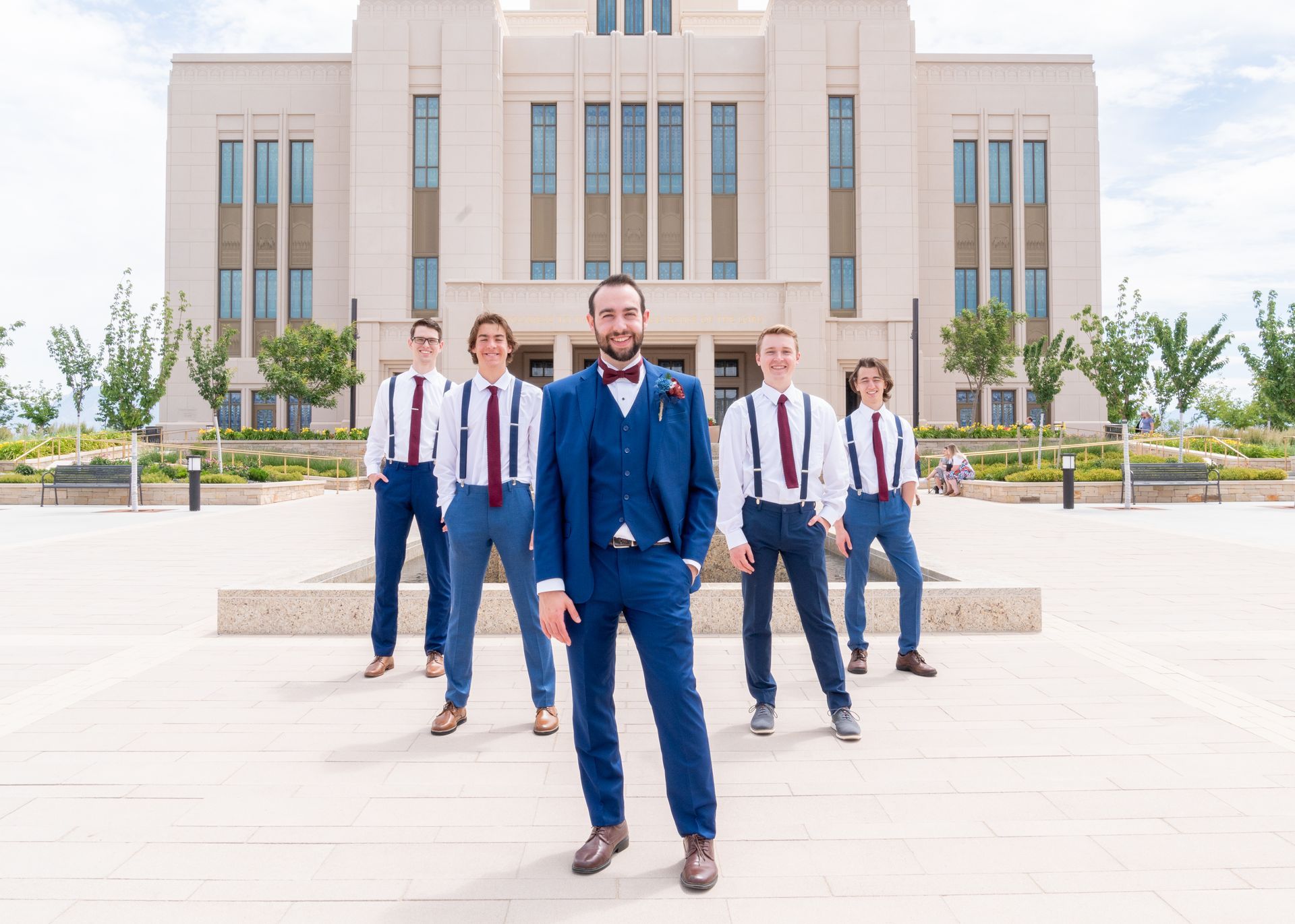 A woman in a white dress is standing next to a tree with red roses.