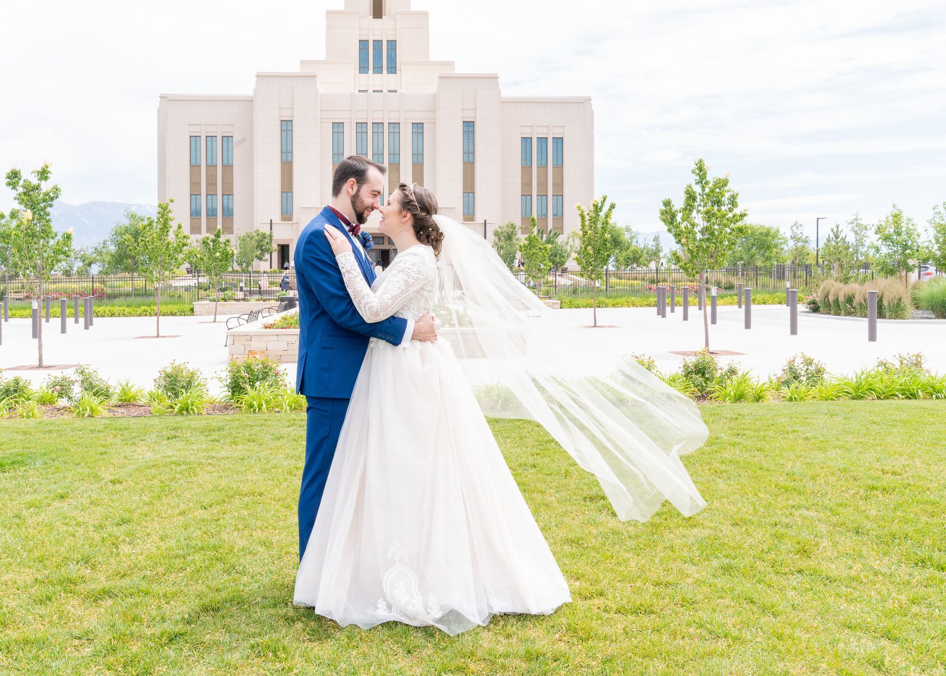 A bride and groom are kissing in front of a temple.