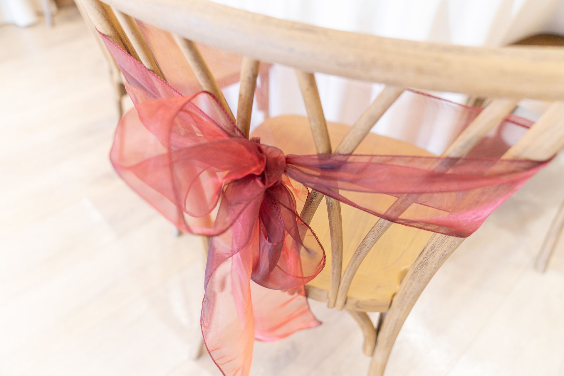 A wooden chair with a red ribbon tied around it.
