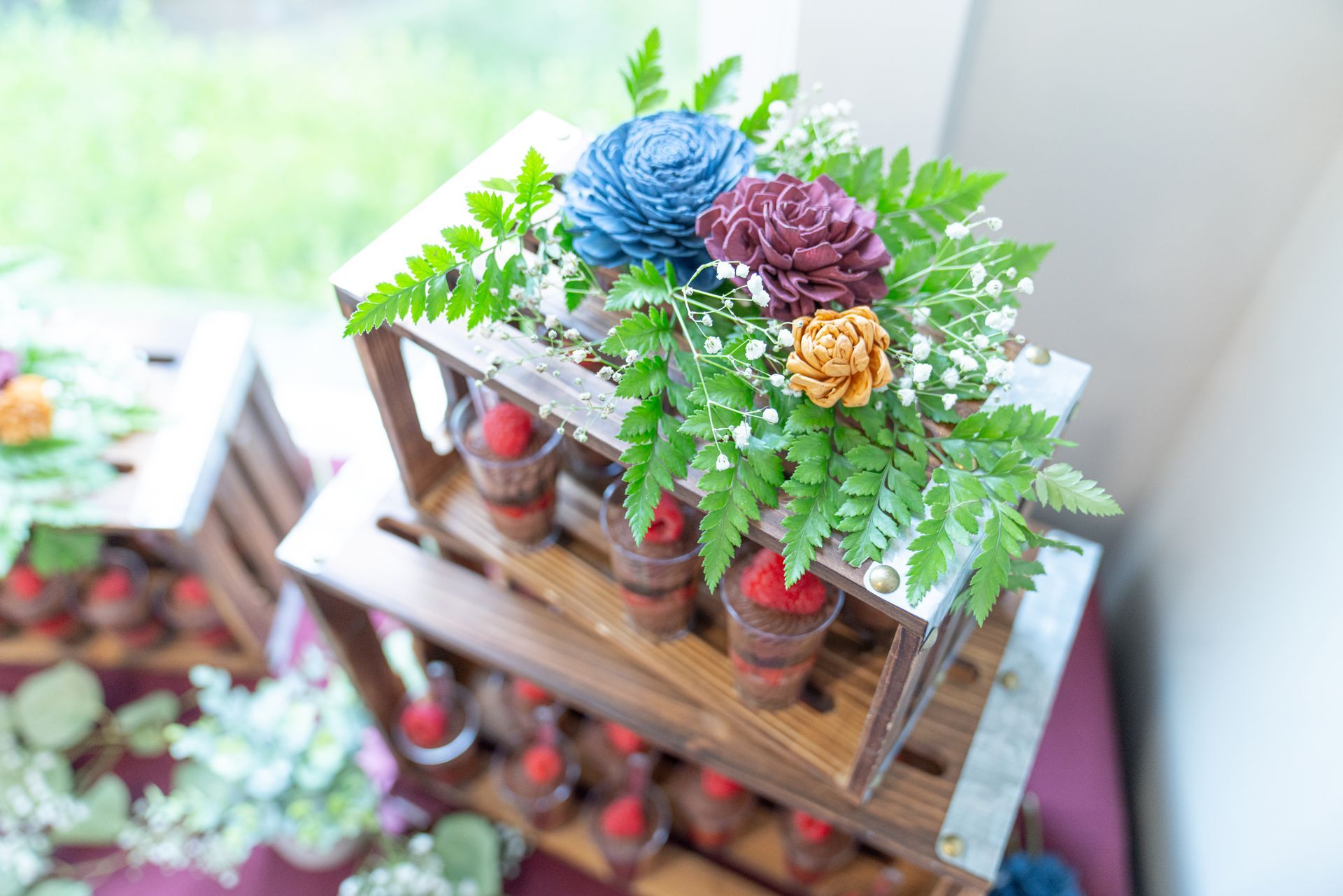 A wooden crate filled with flowers and candles on a table.