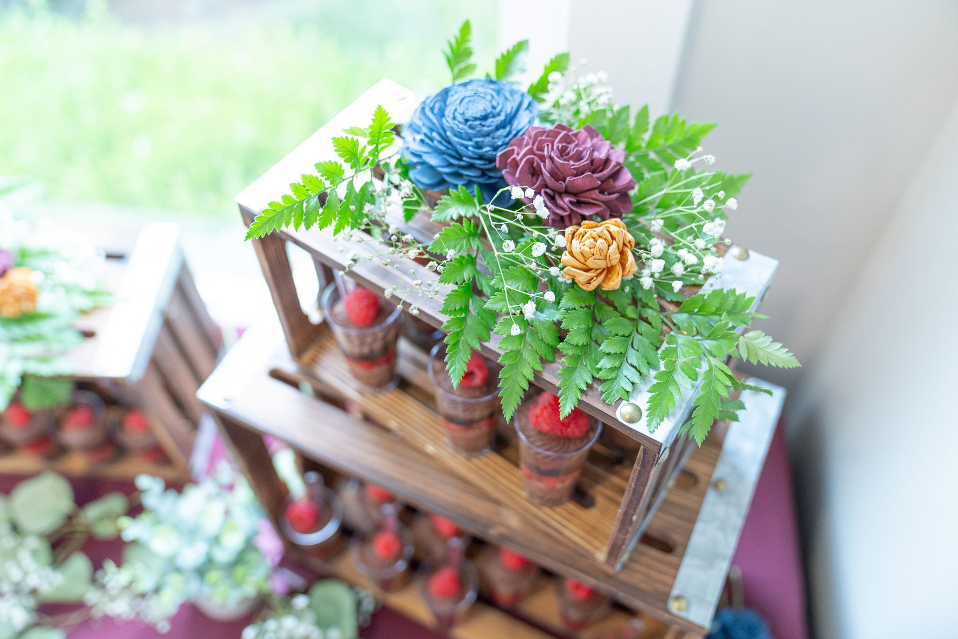A wooden crate filled with flowers and candles on a table.