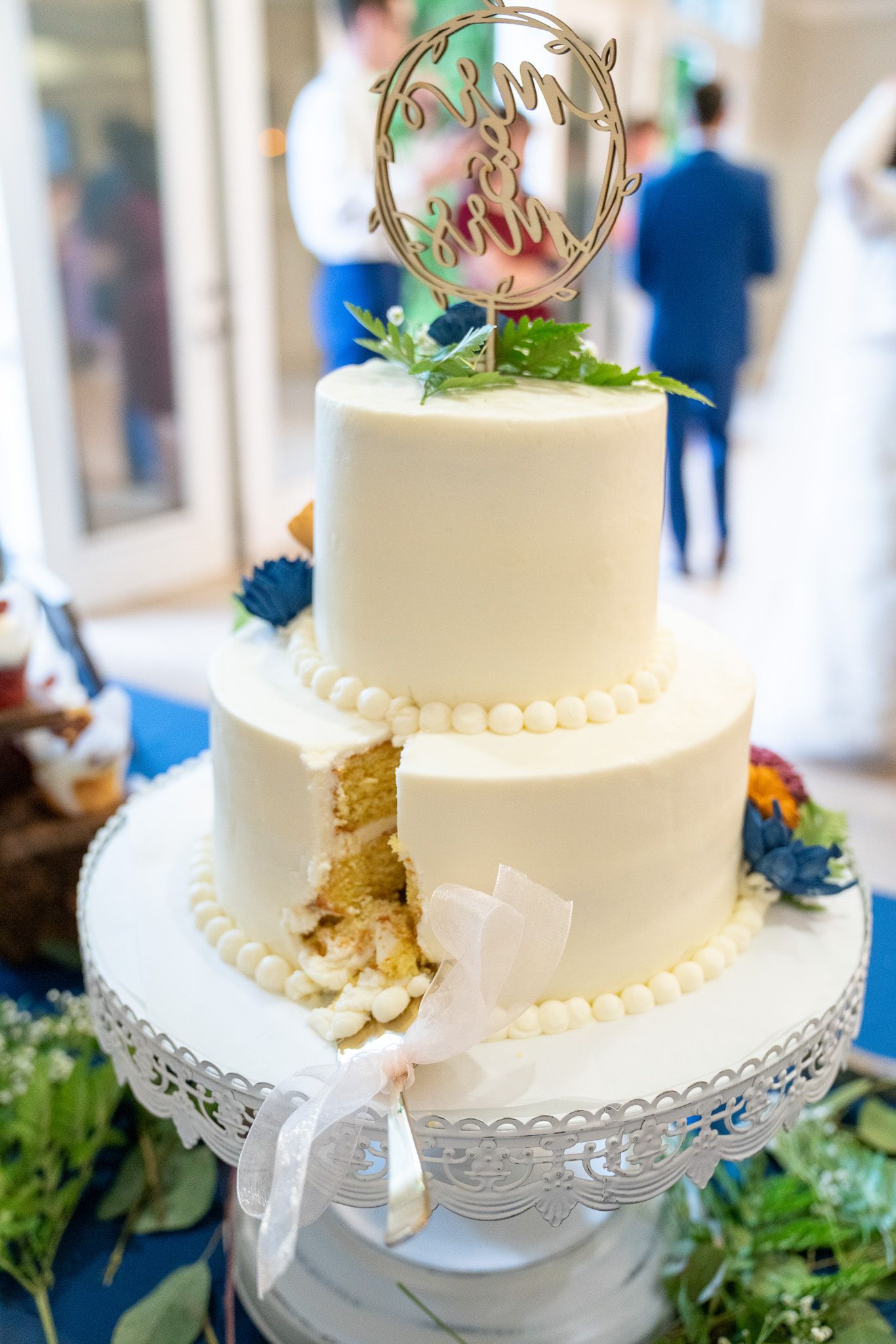 A wedding cake with a slice taken out of it is on a table.
