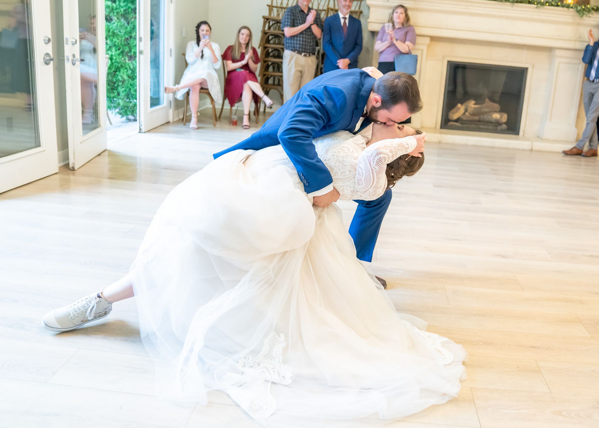 A bride and groom are kissing during their first dance at their wedding reception.