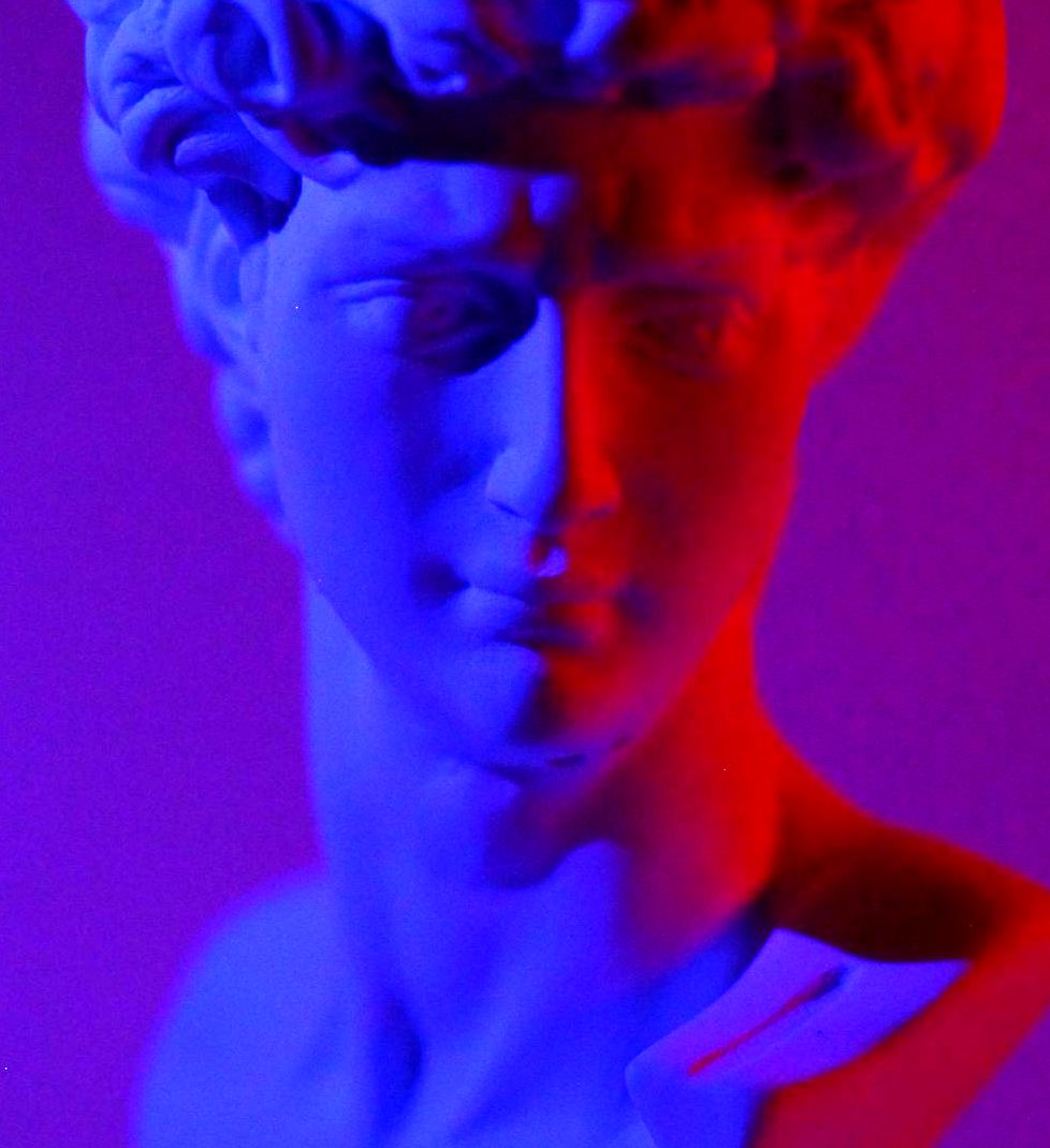 A close up of a statue of a man 's head in blue and red light.