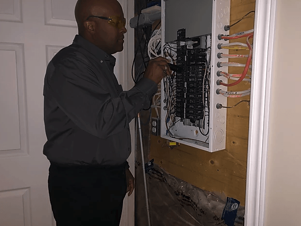 A man is working on an electrical box in a room.