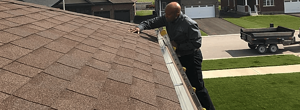 A man is standing on the edge of a roof holding a basketball.