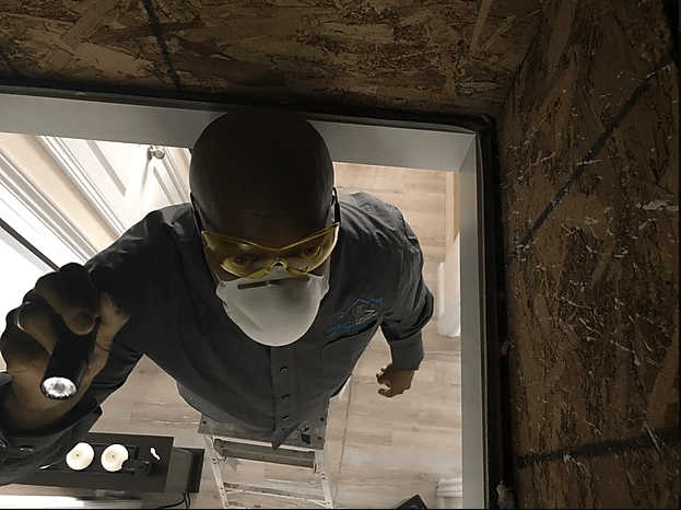 A man wearing a mask and goggles is looking through a doorway.