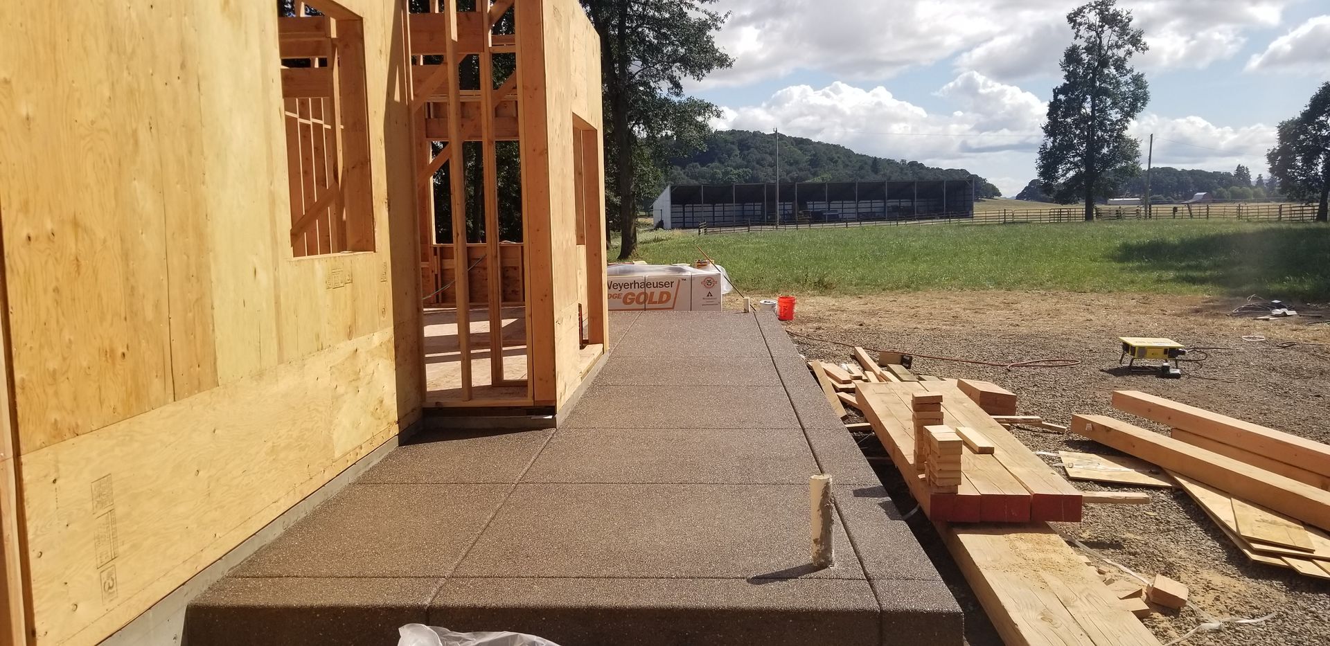 A wooden house is being built in a field.