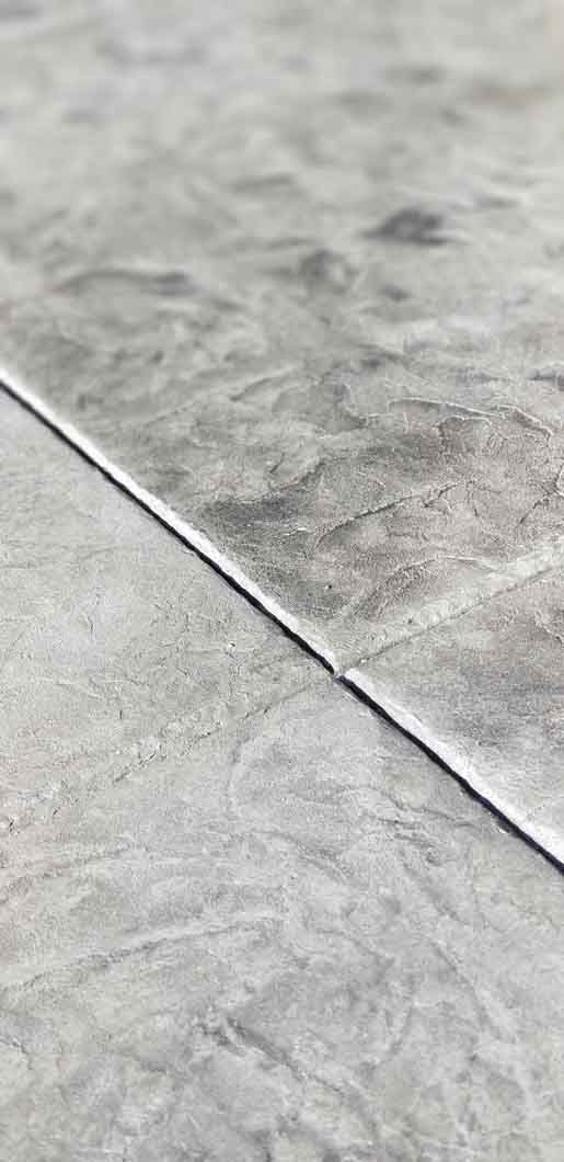 A close up of a gray tile floor with a white border.