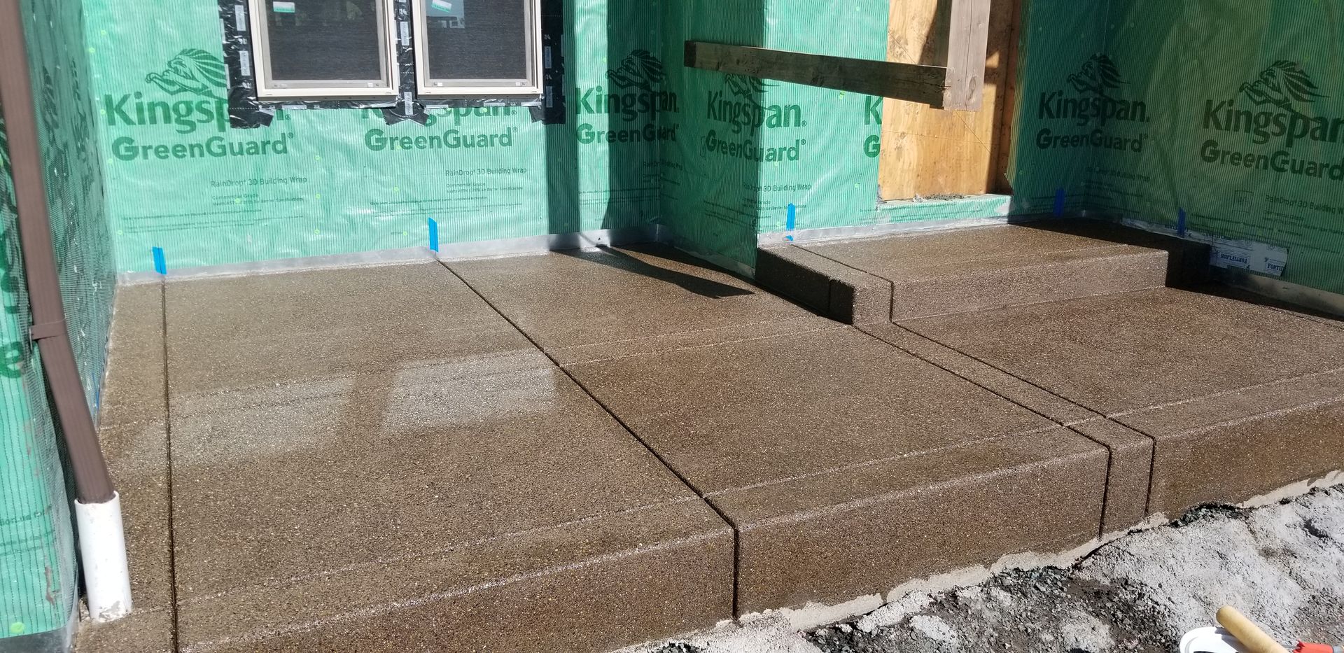 A concrete walkway is being built in front of a house.