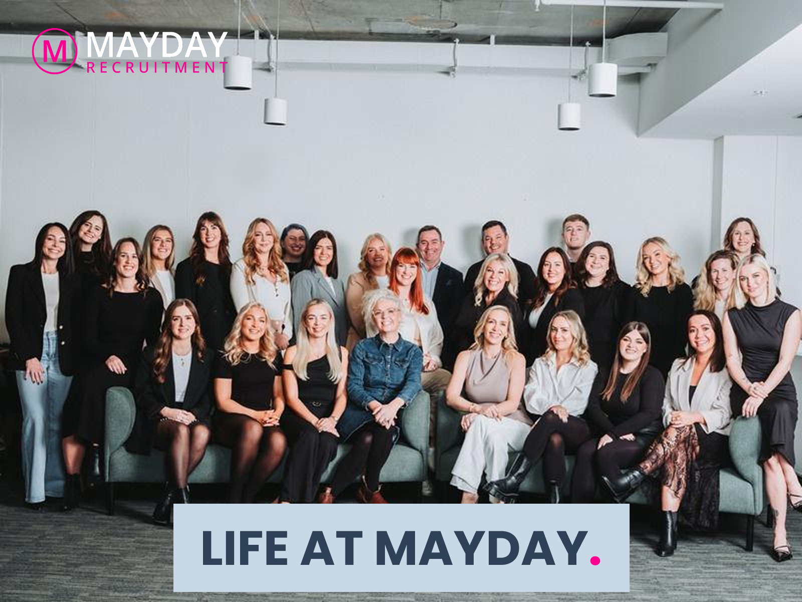 Group photo of Mayday employees in a bright office, with “LIFE AT MAYDAY.” banner at the bottom.