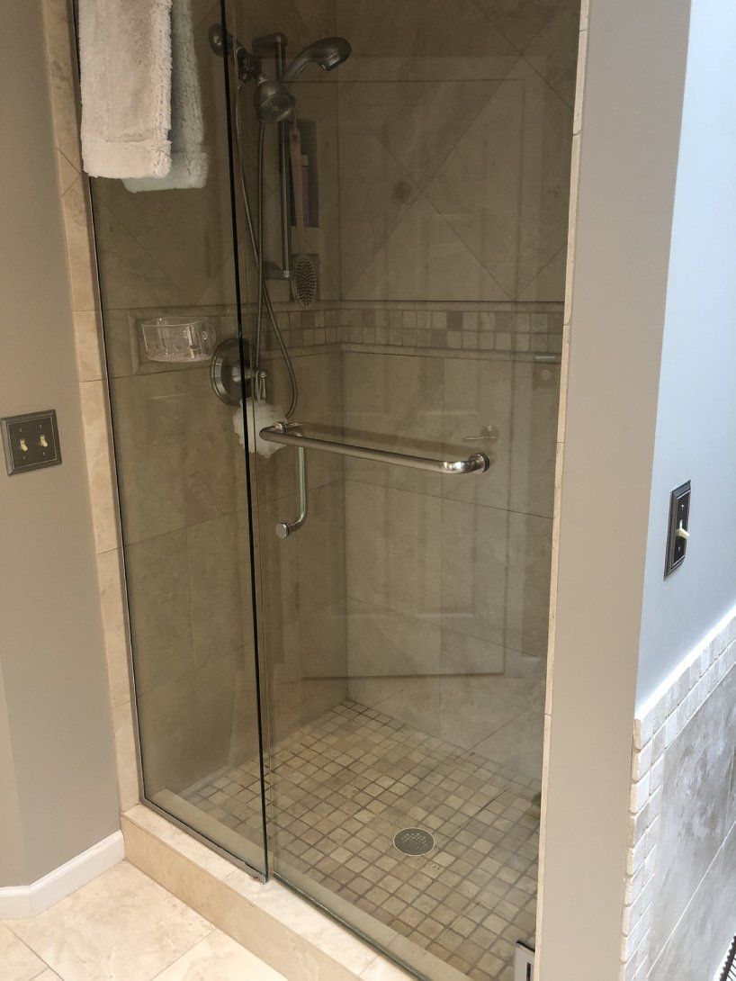 a bathroom with a walk in shower with a glass door .