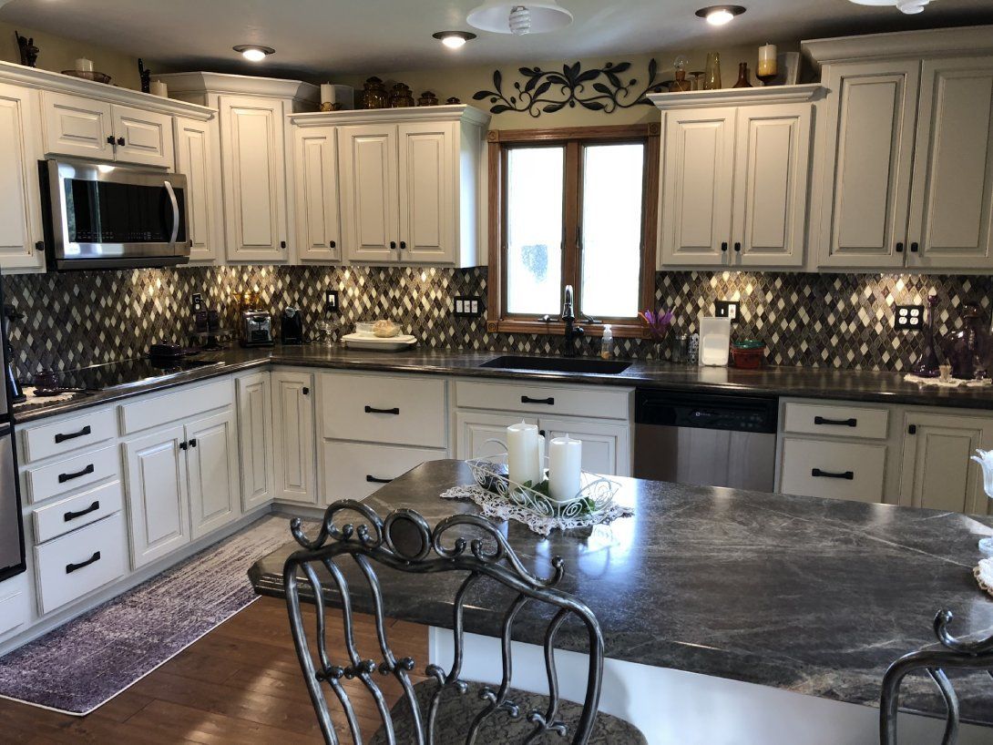 a kitchen with white cabinets and granite counter tops