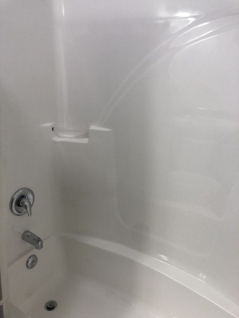 a white bathtub with a chrome shower head and faucet in a bathroom .