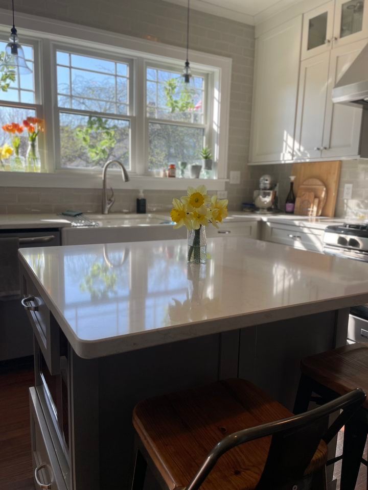 a kitchen with a large island and a vase of flowers on the counter .
