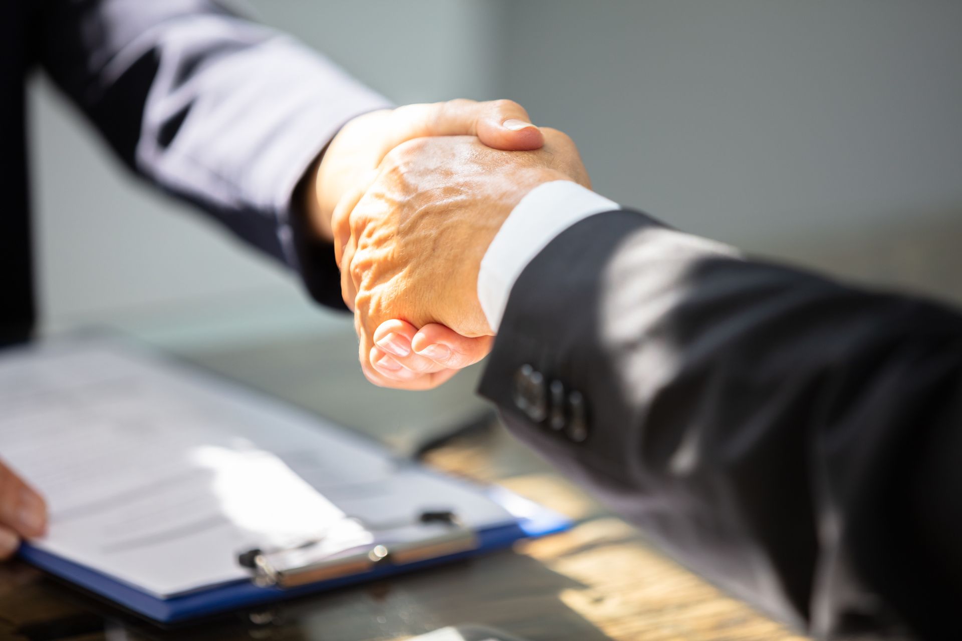 Two Businessmen Are Shaking Hands in Front of a Clipboard | Bowral, NSW | KQ Lawyers