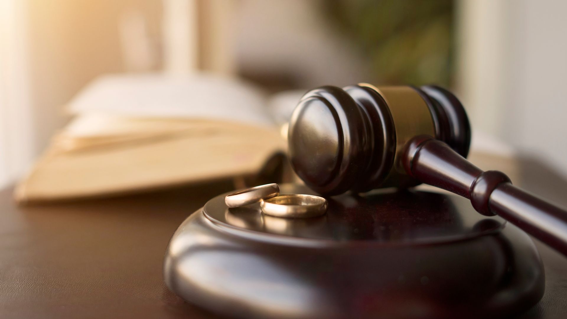 Judge’s gavel beside wedding rings symbolizing divorce proceedings. Judge’s gavel beside wedding rings symbolizing divorce proceedings.