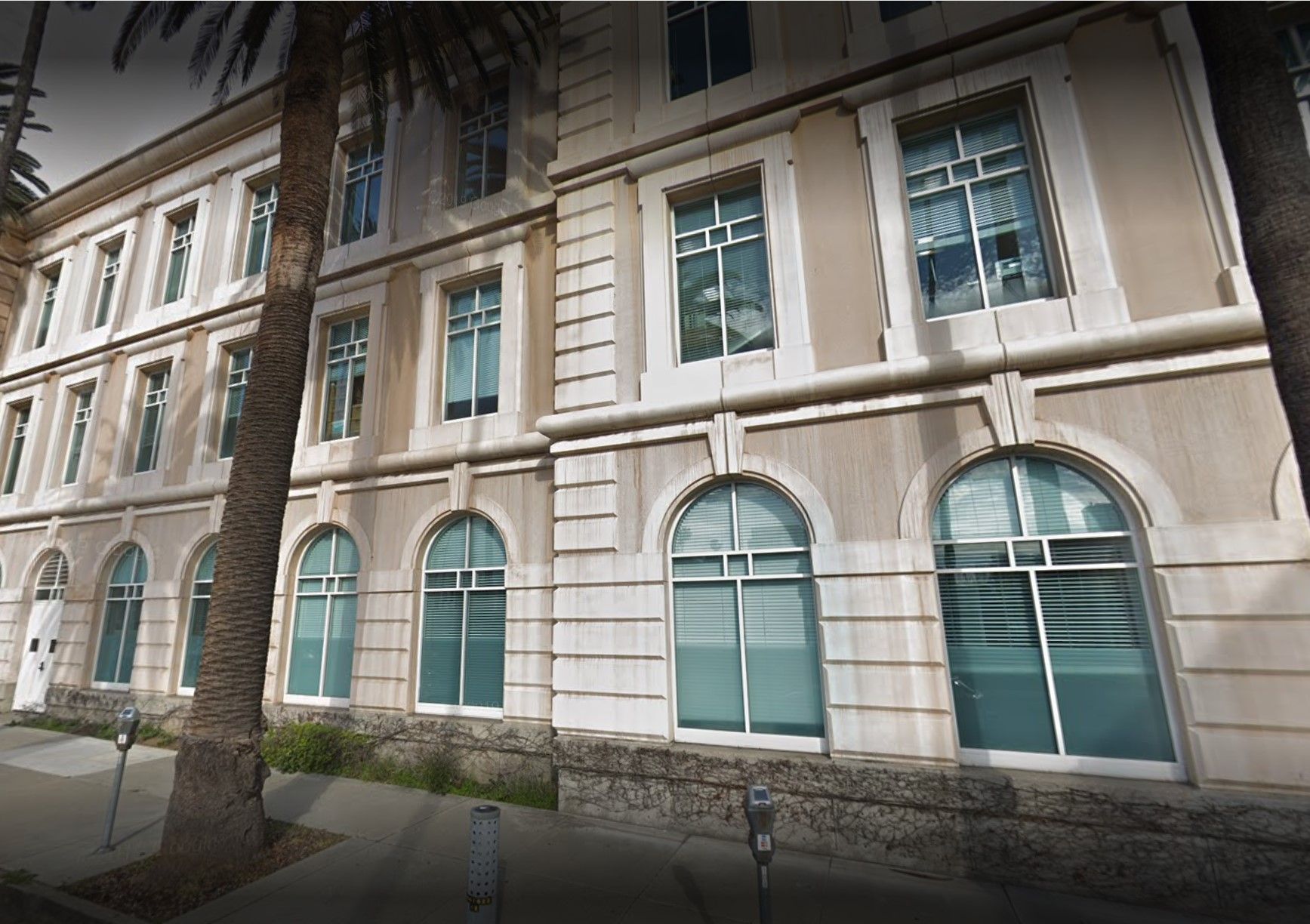 A large building with a lot of windows and palm trees in front of it