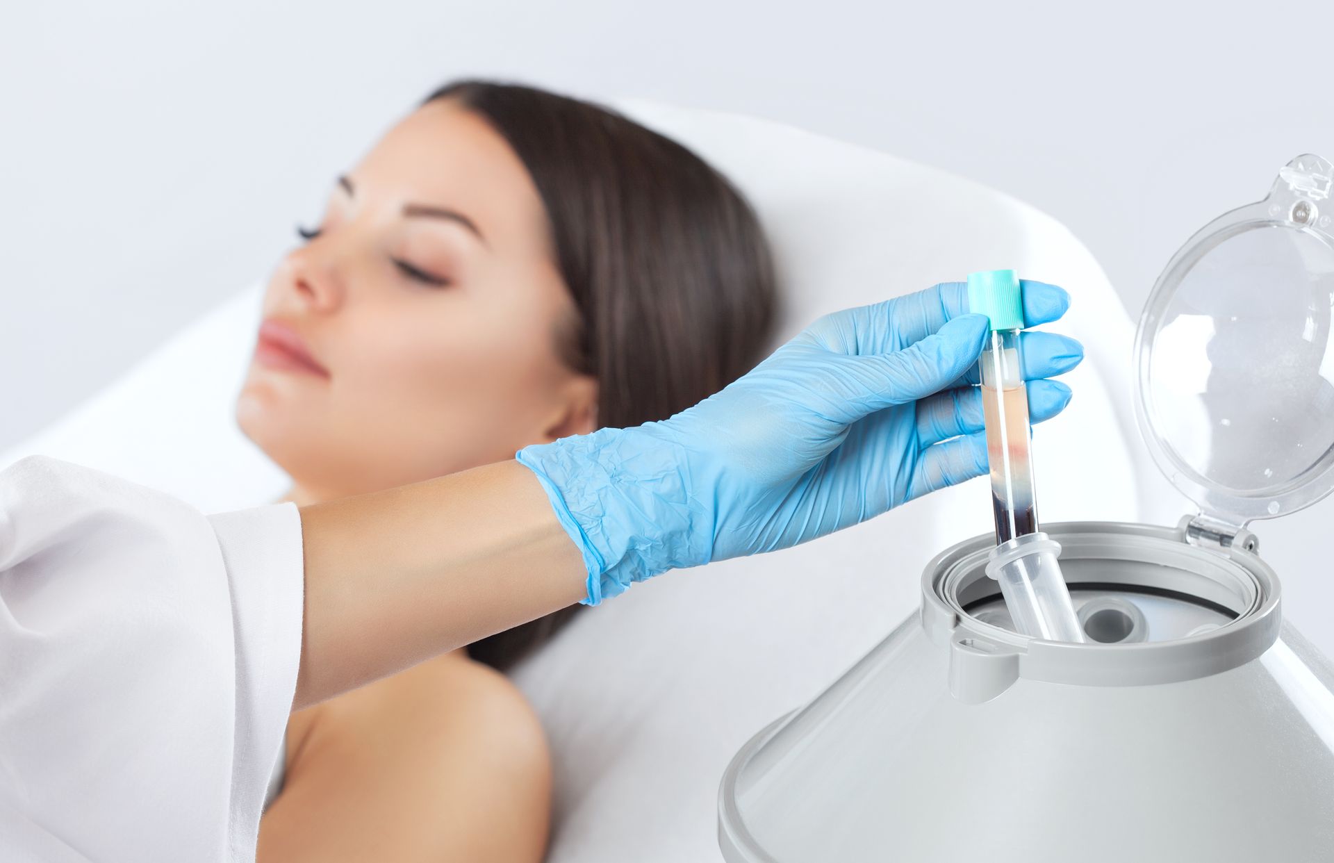 A woman is laying in a bed while a doctor is holding a test tube.