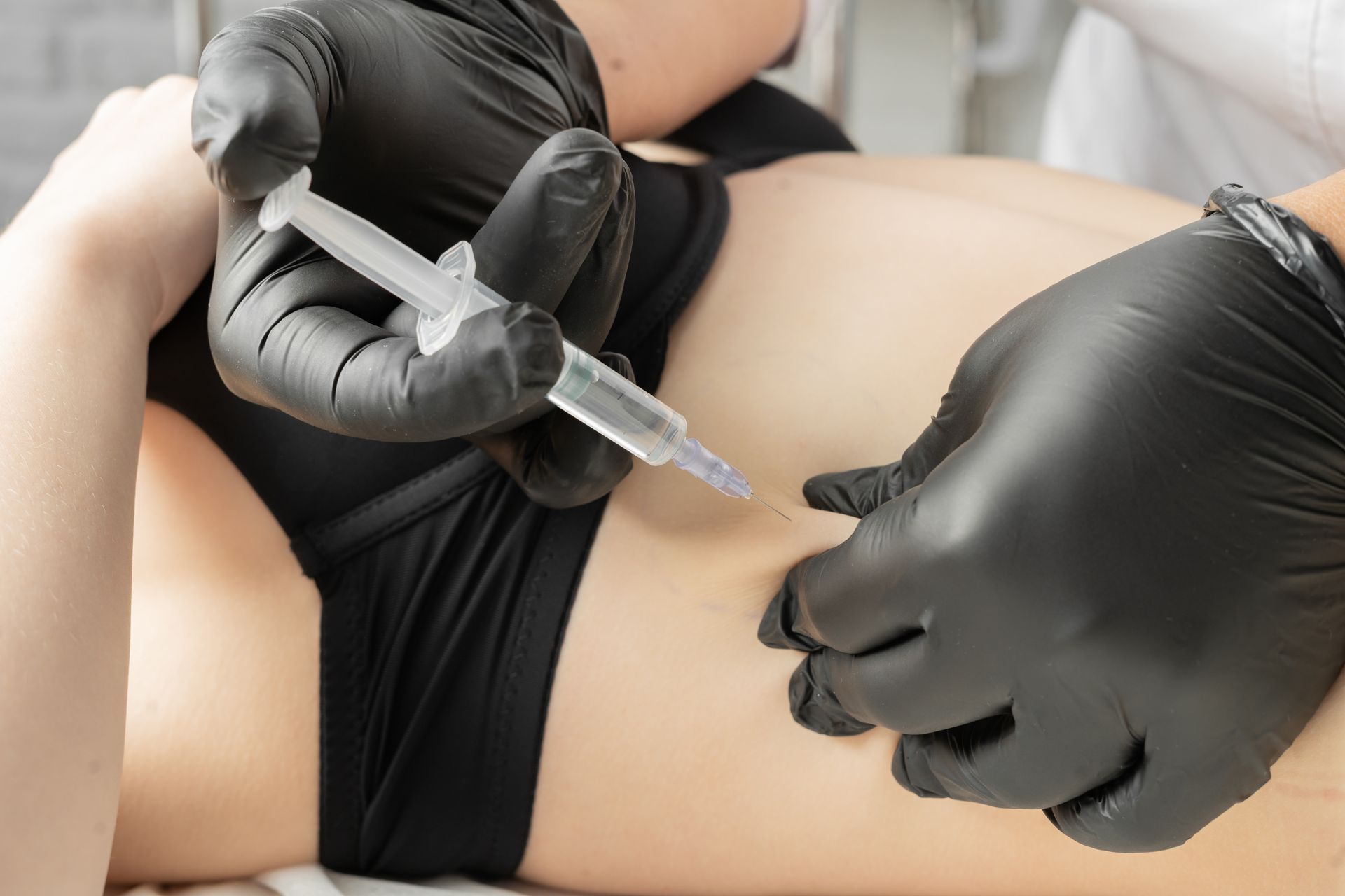 A woman is getting an injection in her stomach.