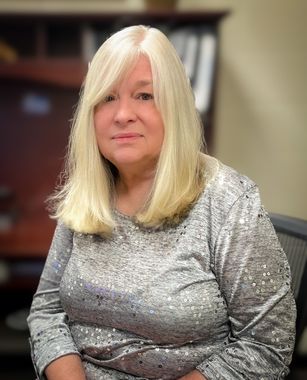 A woman with blonde hair is sitting in a chair in an office.