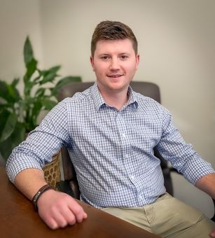 A man in a plaid shirt is sitting at a table.