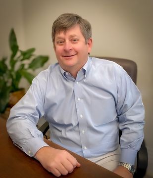 A man in a blue shirt is sitting at a desk