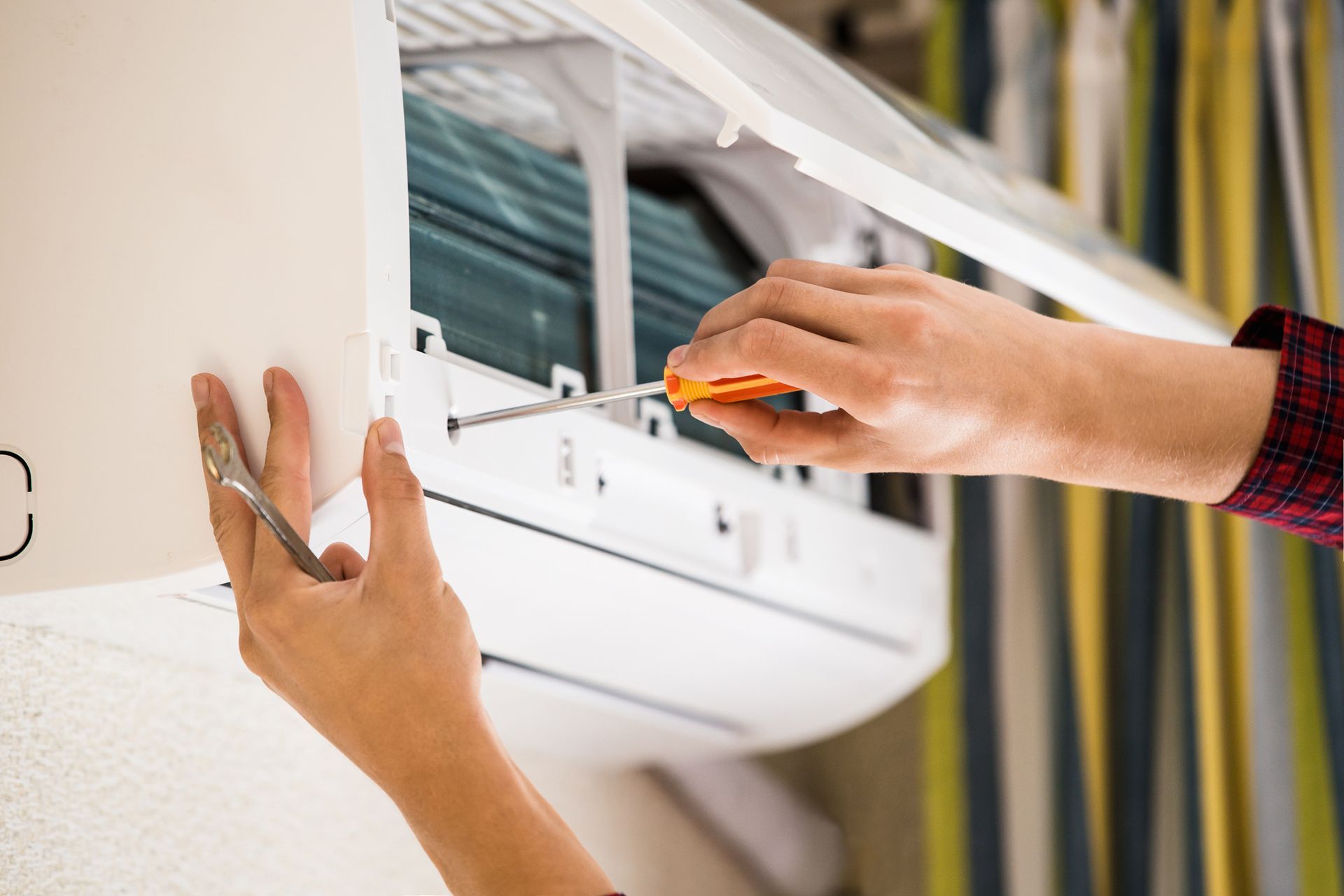An air conditioning service technician repairing a wall-mounted AC unit.