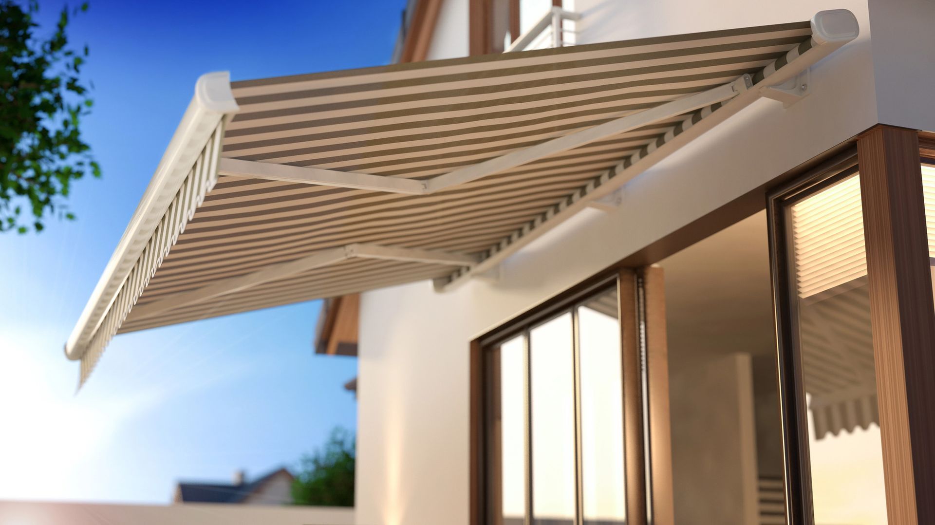 Esterno di una casa moderna con una tenda da sole retrattile beige che si estende sopra le porte a vetri.