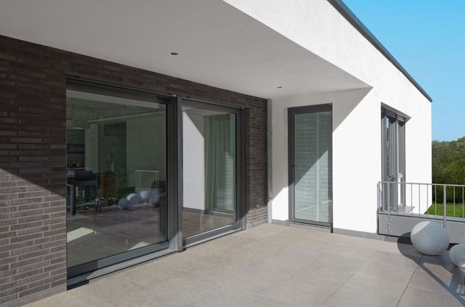 Patio moderno con ampie porte scorrevoli in vetro e pareti esterne bianche.