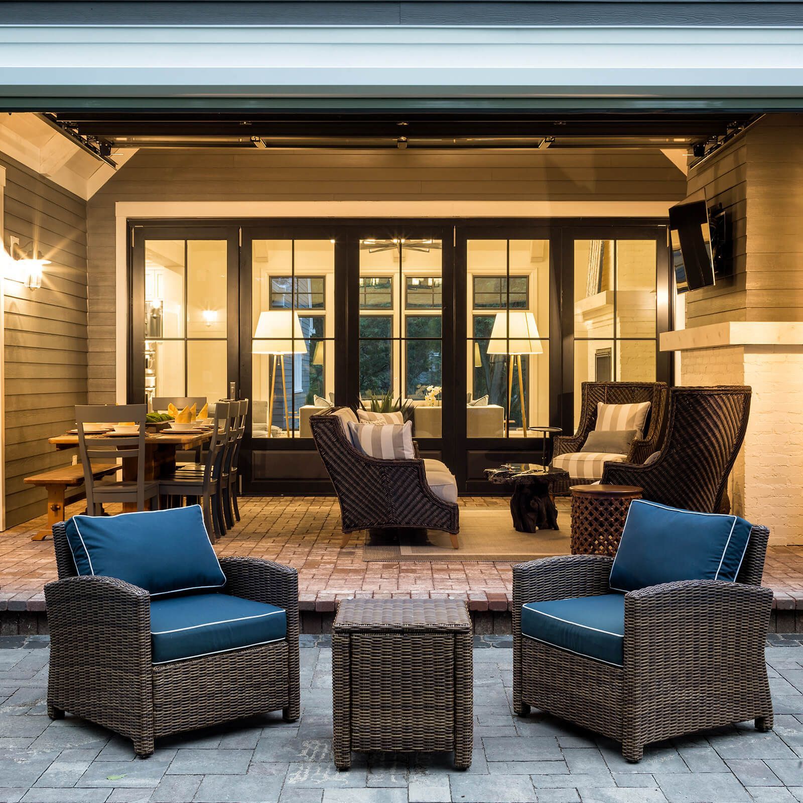 A patio with wicker chairs and tables with blue cushions