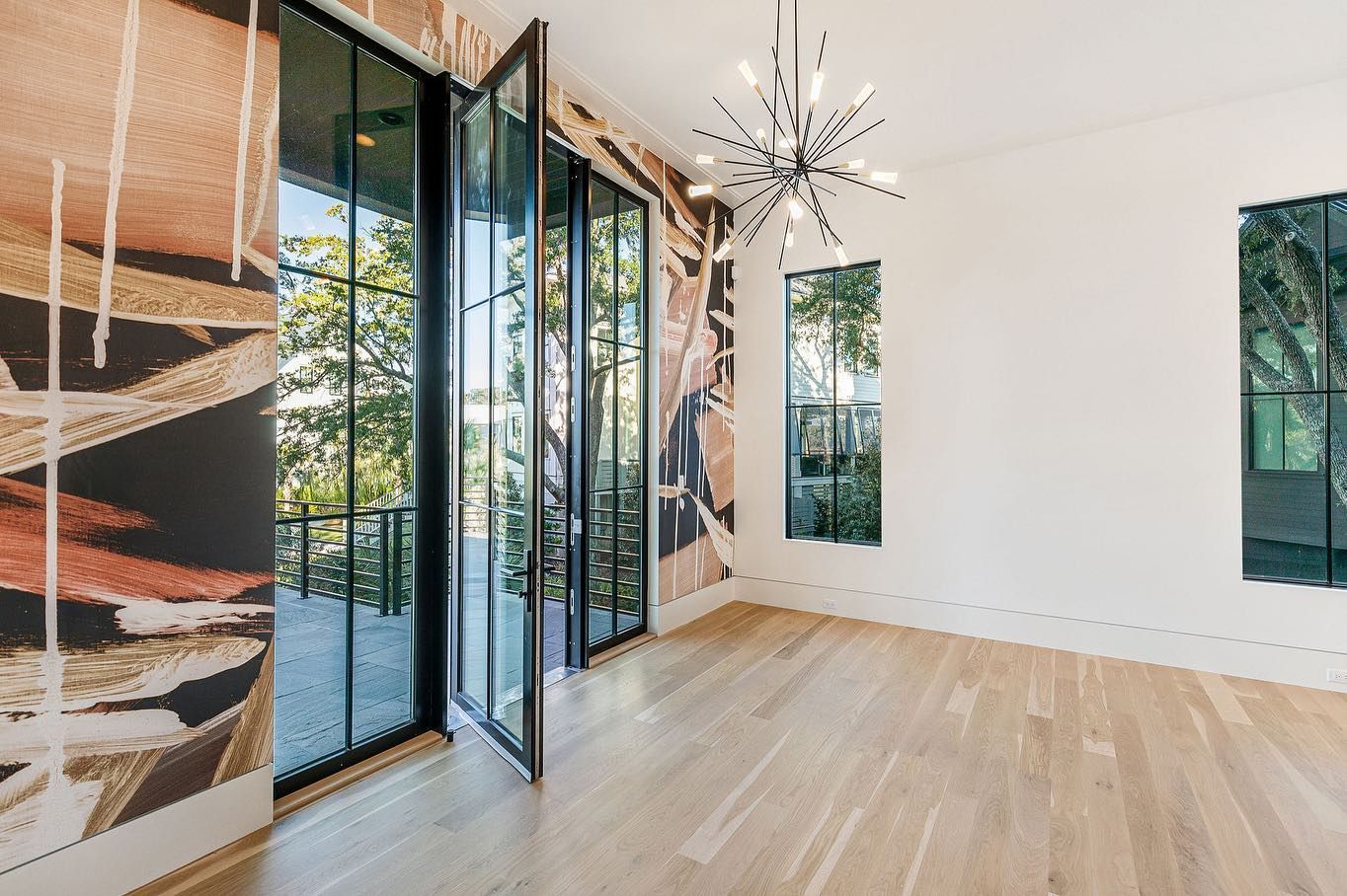 An empty room with a lot of windows and a chandelier.