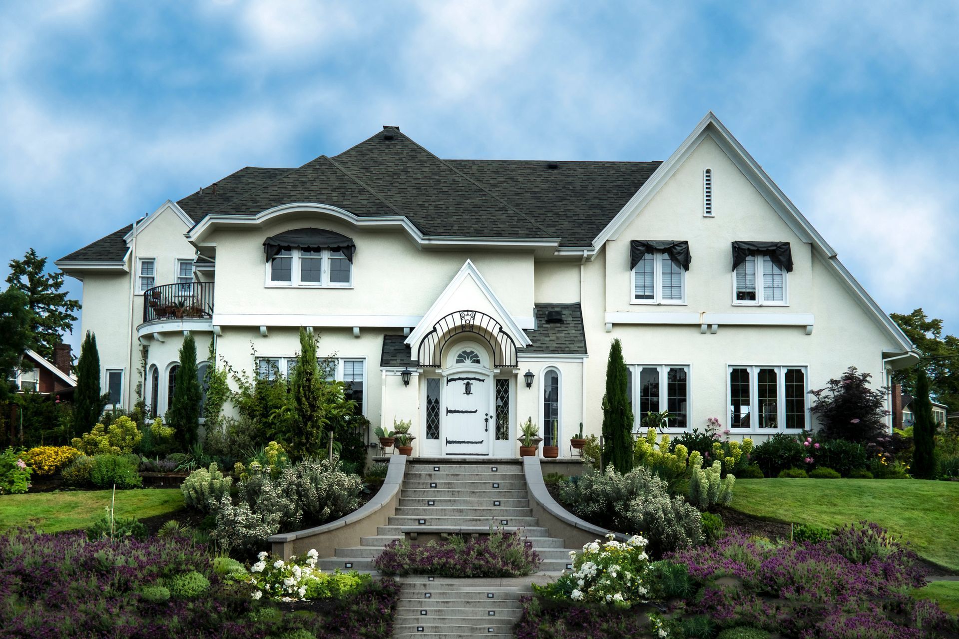 White two-story house with dark roof, garden steps leading to the front door. Blue sky.