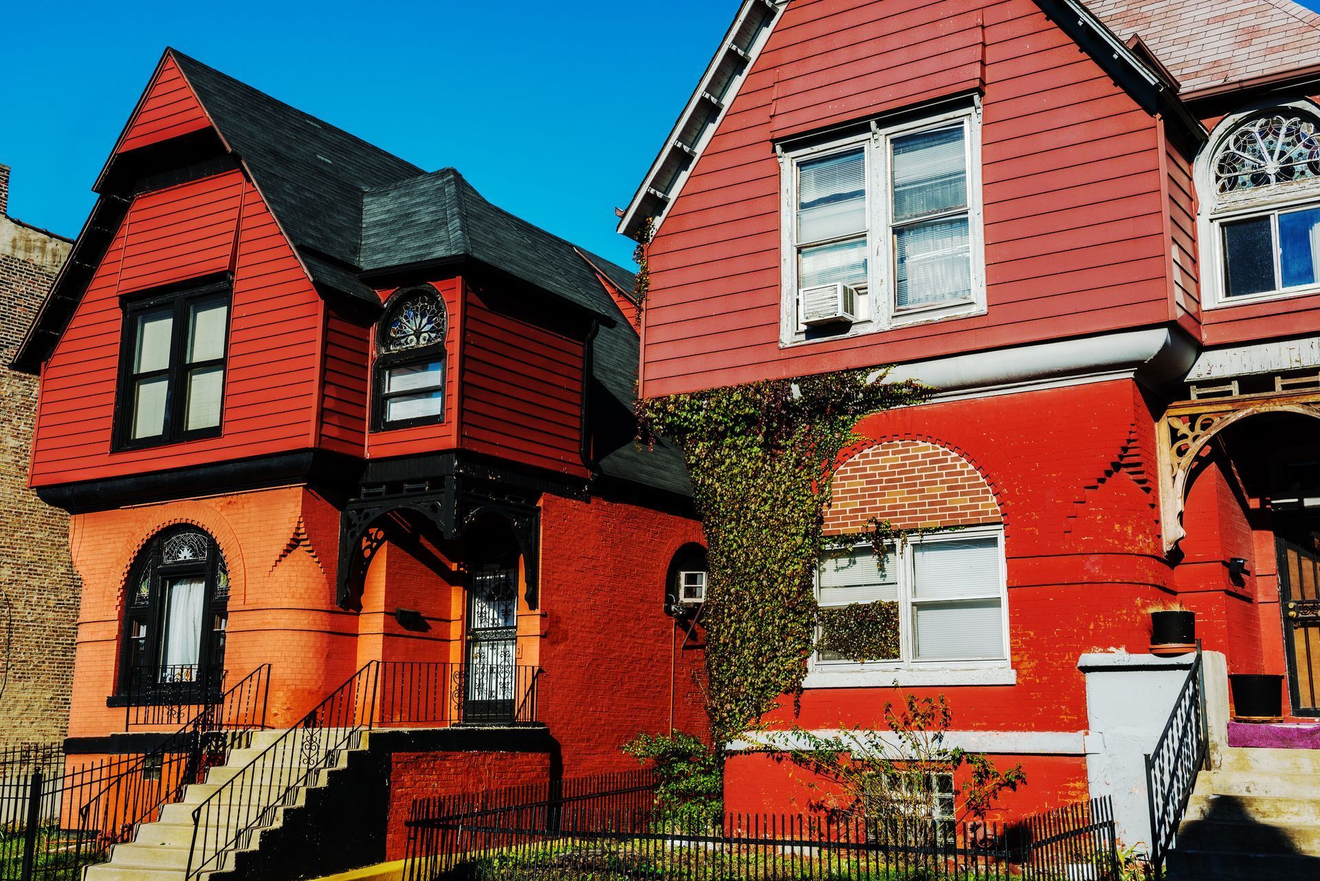 Red and orange Victorian-style houses with dark trim under a clear blue sky. Red and orange Victorian-style houses with dark trim under a clear blue sky.