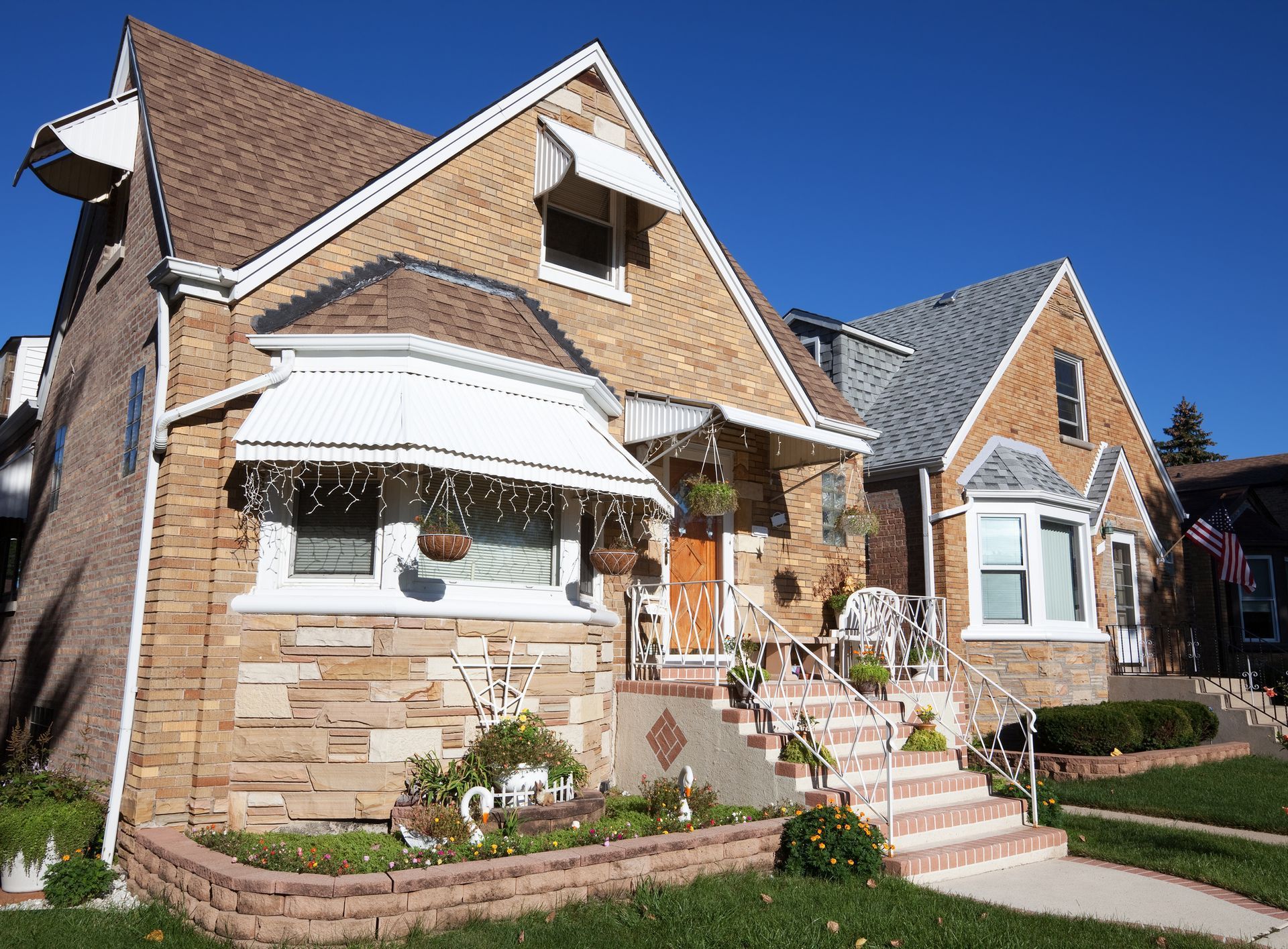 Two-story brick houses with gabled roofs and awnings against a clear blue sky. Two-story brick houses with gabled roofs and awnings against a clear blue sky.