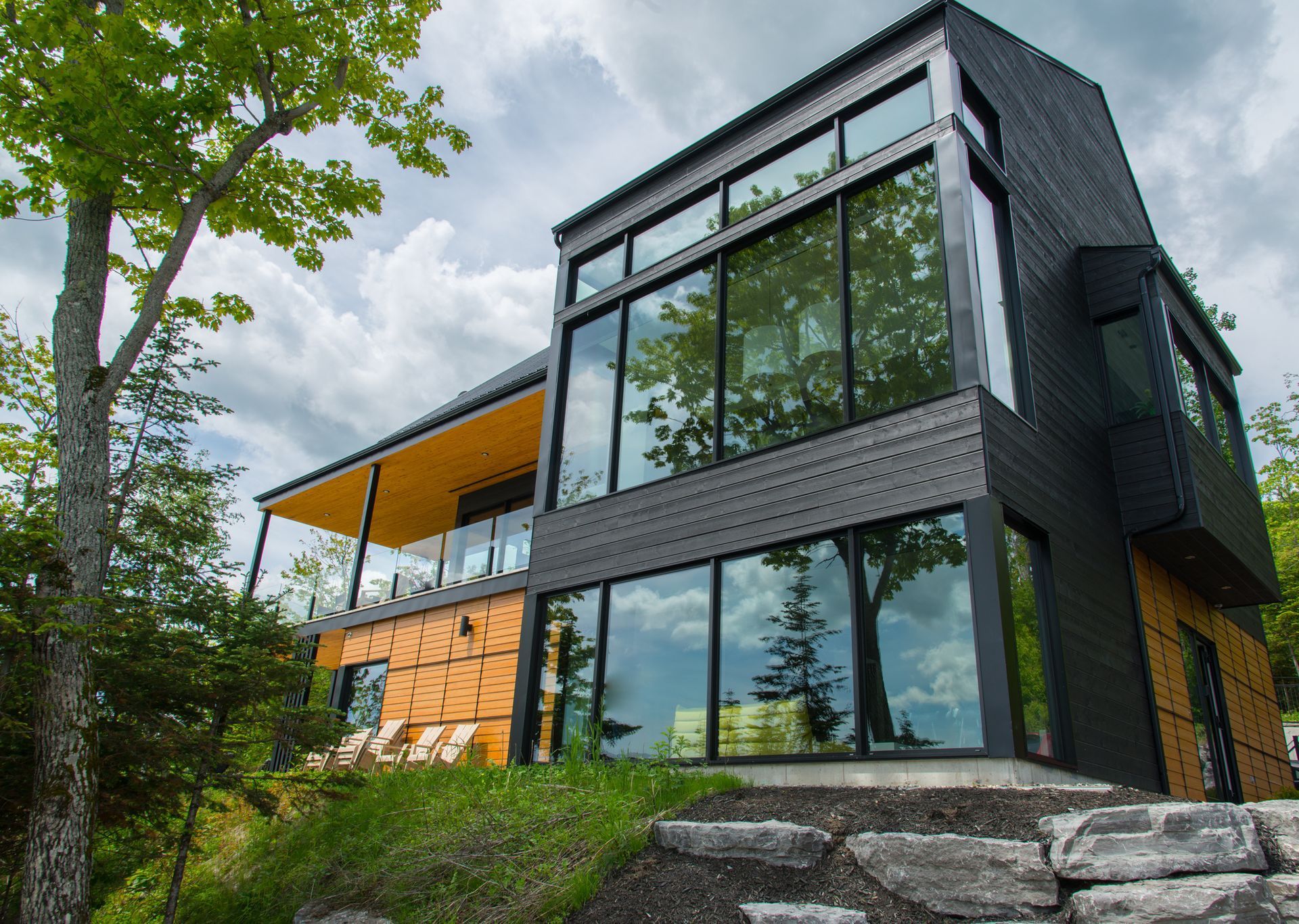 Modern home with black exterior, large windows, wooden accents, and a covered porch.