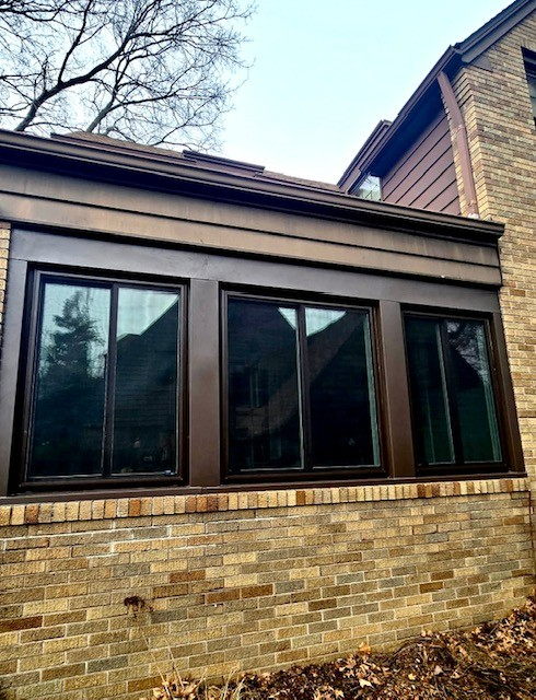 Brown-framed windows on a brick building with matching trim. Sunny outdoor setting.