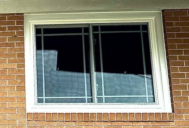 White-framed sliding window with black bars on a red brick building.