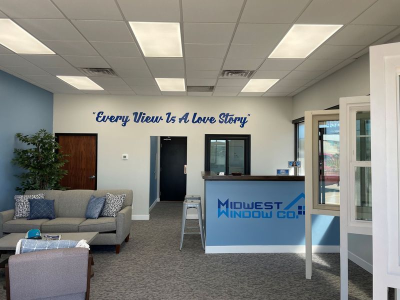 Interior of Midwest Window Co. showroom with reception desk and seating area. Blue and white colors. Text on wall: 